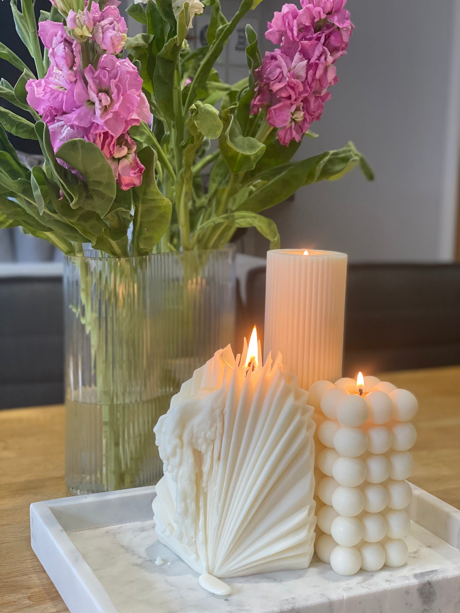 Pillar candles styled on a dining table with flowers, creating a warm and inviting candlelight setting.
