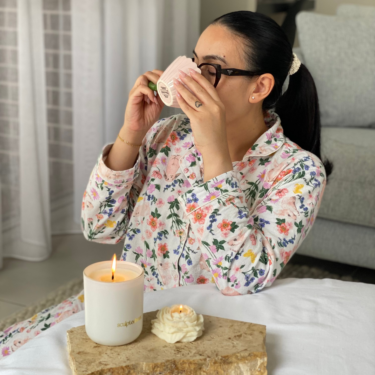 Woman enjoying coffee with sculptural candle set, featuring soy candle, peony candle and pink mug in a calm morning setting