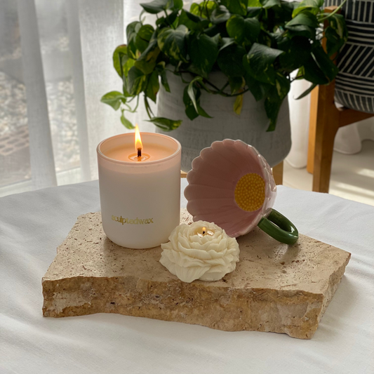 Peony sculptural candle made from natural soy wax beside a softly burning jar candle in a calm home setting